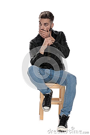 Man sitting on chair with hand at chin looking amazed Stock Photo