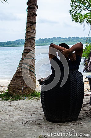 Man Sitting on a Chair relaxing at the beach Stock Photo