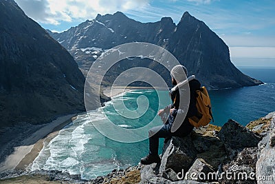 Man sitting on cliff edge alone enjoying aerial view backpacking lifestyle travel adventure outdoor vacations in Norway Stock Photo