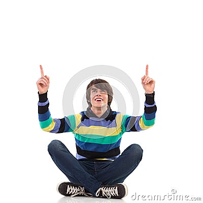 Man sitting with crossed legs on the floor, pointing up Stock Photo