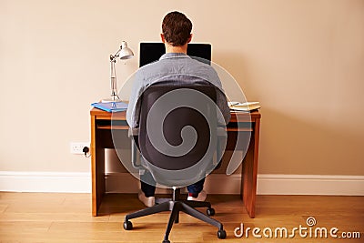 Man Sitting At Desk Working At Computer In Home Office Stock Photo