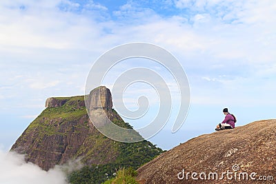 Man sitting on edge of mountain Pedra Bonita, Pedra da Gavea Stock Photo