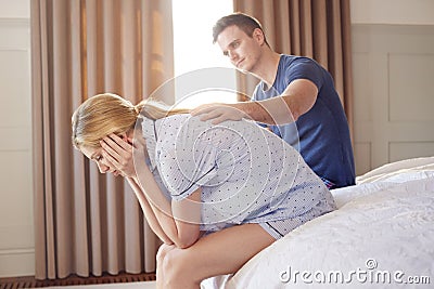 Man Sitting On End Of Bed At Home Comforting Woman Suffering With Mental Health Issues Stock Photo