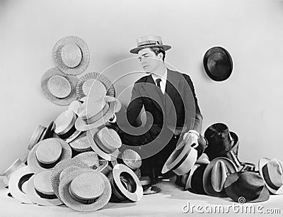 Man sitting on the floor surrounded by hats Stock Photo