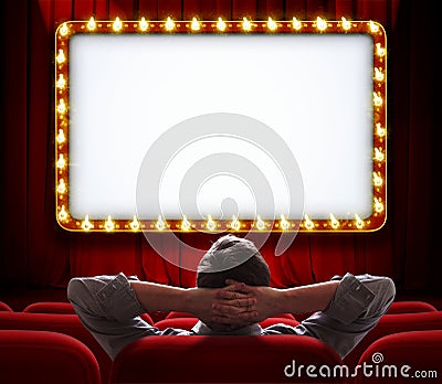 Man sitting in front of lighted sign on red theatre curtain Stock Photo