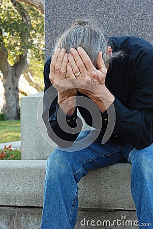 Man sitting at gravesite Stock Photo