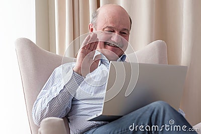 Man sitting in the living room and having videochat on the laptop computer Stock Photo