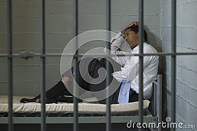 Man Sitting In Prison Cell Stock Photo