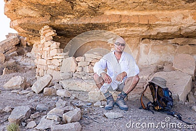 Man sitting resting moutains rock cliff shelter. Stock Photo