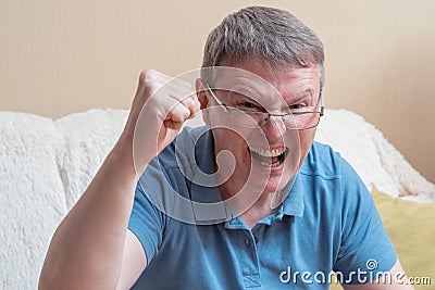 Man sitting on sofa. Excited Man Celebrate Watching Sports On Television Stock Photo