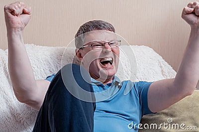 Man sitting on sofa. Excited Man Celebrate Watching Sports On Television Stock Photo