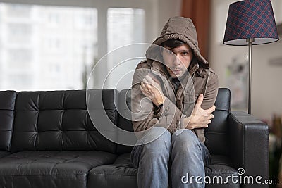 Man is sitting on sofa at home and feeling cold. Stock Photo