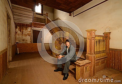Man Sitting on Stairs in an Old House Stock Photo