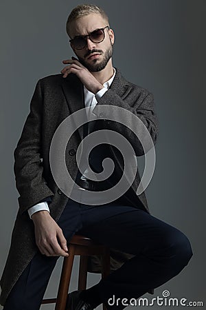 Man sitting on a stool with hand on beard Stock Photo