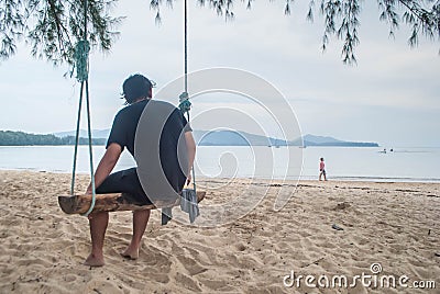 A man sitting on wooden swing on the layan beach in phuket, Thai Editorial Stock Photo