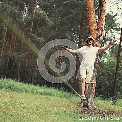 Man slacklining walking and balancing on a rope, slackline in forest Stock Photo