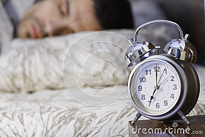 A man sleeping close to a retro alarm clock Stock Photo