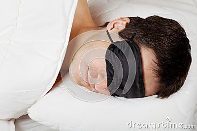Man with Sleeping mask lying in bed Stock Photo
