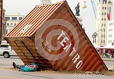 Man sleeping under half buried container Editorial Stock Photo