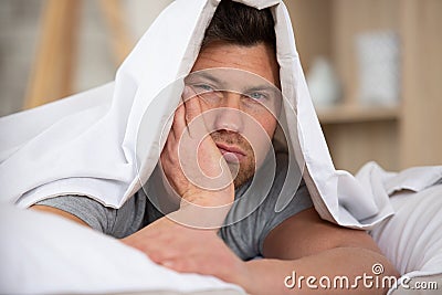 Man sleepy drowsy unshaven bearded face covered with blanket Stock Photo