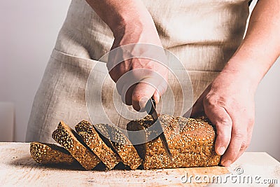 A man slices large knife with fresh bread with golden crust. The concept of home baking cooking diet food without yeast. Stock Photo