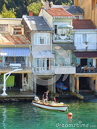 Man in small boat by waterside houses Editorial Stock Photo