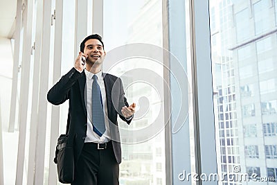 Man on smart phone - young business man in airport. Casual urban professional businessman using smartphone smiling happy. Stock Photo