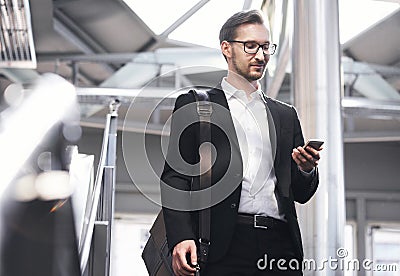 Man on smart phone - young businessman in airport. Handsome men in eyeglasses wearing suit jacket indoors Stock Photo