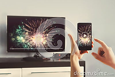 Man With Smartphone Connected To A TV Watching Video At Home Stock Photo