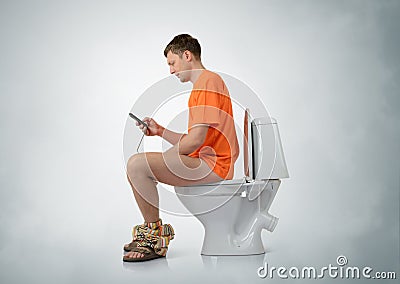 Man with smartphone sitting on the toilet Stock Photo