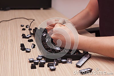 Man smashes a mechanical computer keyboard in rage using both fists Stock Photo