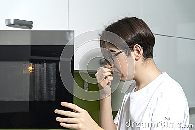 A man smells an unpleasant smell from the microwave in the kitchen Stock Photo