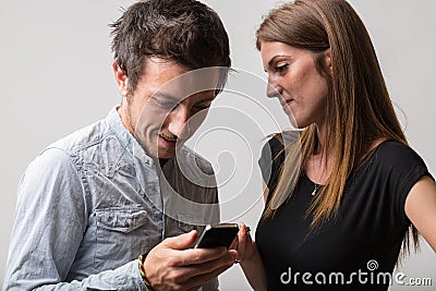 Man smiles at phone, girlfriend indulges Stock Photo