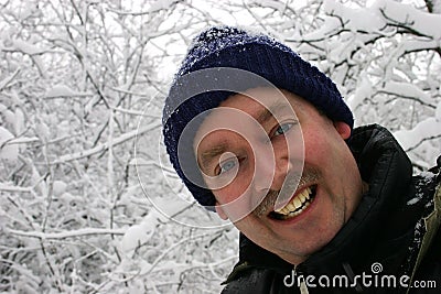 Man Smiling to the Camera while Surrounded by Snow Filled Branch Stock Photo