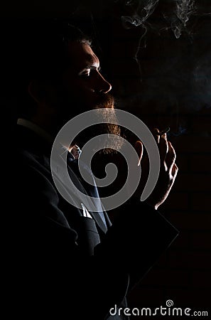 Man smoking cigarette isolated on black. A man smokes cannabis weed, a joint and a lighter in his hands. Smoke on black Stock Photo