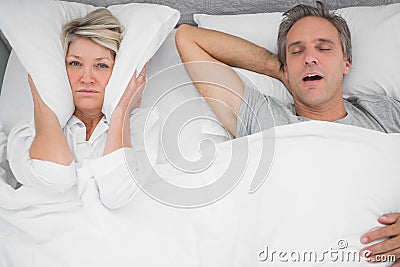 Man snoring loudly as partner blocks her ears Stock Photo