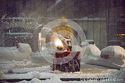 man with a snow blowing machine working and cleaning the city street in winter day during snow blizzard Stock Photo