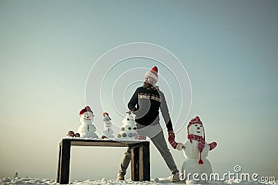 Man and snowman holding hands on blue sky Stock Photo