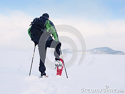Man with snowshoes and backpack take photos by smartphone. Hiker in snowdrift Stock Photo