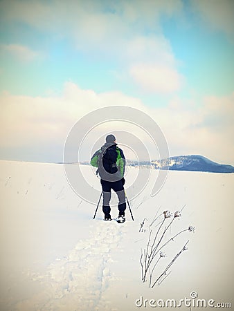 Man with snowshoes take a rest in snow. Hiker snowshoeing Stock Photo
