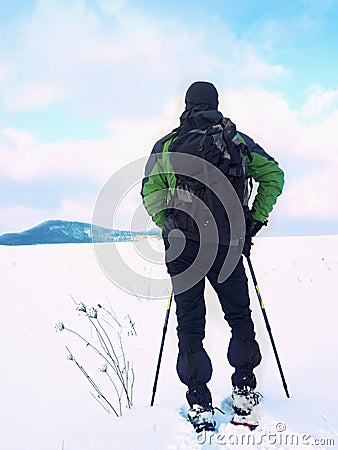 Man with snowshoes take a rest in snow. Hiker snowshoeing Stock Photo