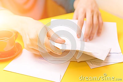 A man sorts the mail. Male hands the envelopes on a yellow background, a red coffee Cup. Stock Photo