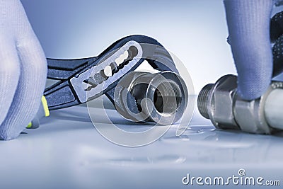 A man with a spanner eliminates the leak in the pipe Stock Photo