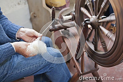 Man spinning wool on a traditional spinning wheel. Stock Photo