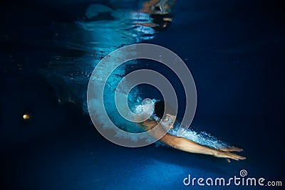 Man with splash swimming under dark blue water Stock Photo