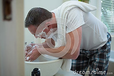 Man spraying water on his face after shaving in the bathroom Stock Photo