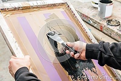 Man squeegeeing silkscreen in a workshop. Serigraphy Stock Photo