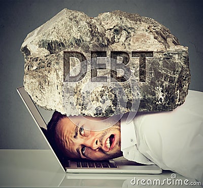 Man squeezed between laptop and rock. Student loan debt concept Stock Photo