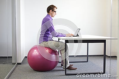 Man on stability ball working with tablet Stock Photo