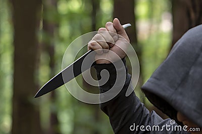 A man stabs with a large knife from above in the forest, close-up, selective focus. The concept: an attack on passers-by, a rapist Stock Photo